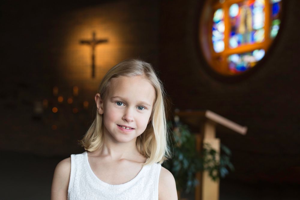 religious first communion girl in chapel with stained glass