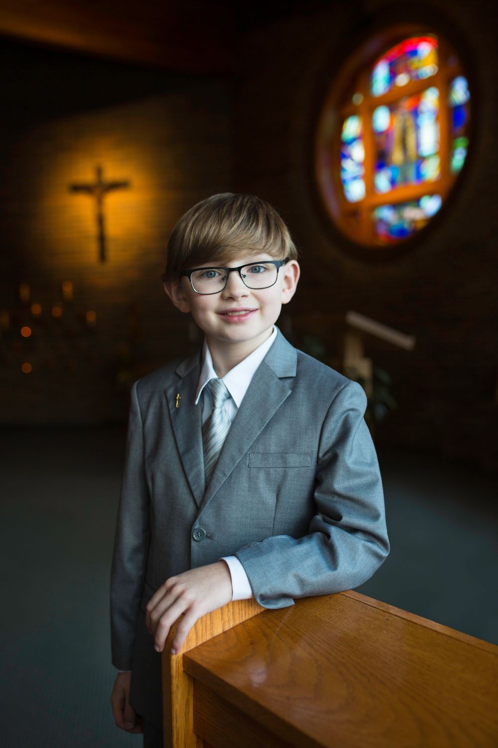 religious first communion boy in chapel with crucifix and stained glass
