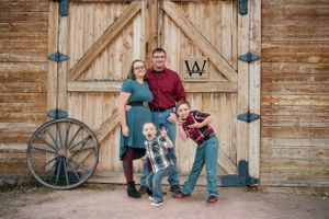 Family of 4 getting family photos in front of the beautiful barn at Rock Ledge Ranch in Colorado Springs,CO