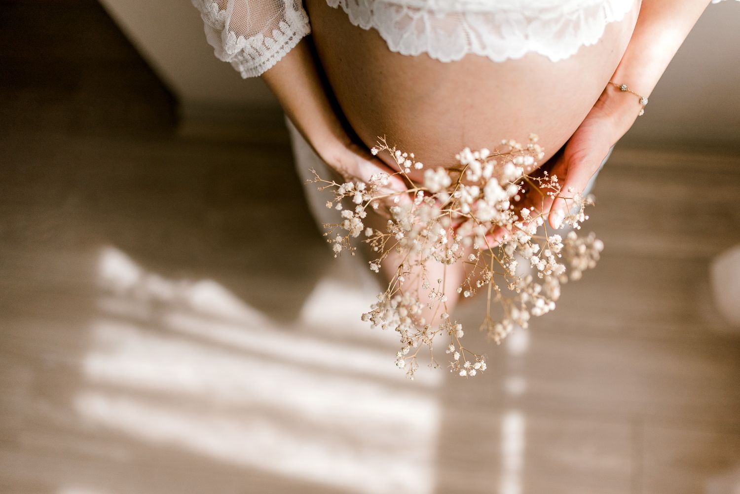 lace gown worn by pregnant lady holding flowers