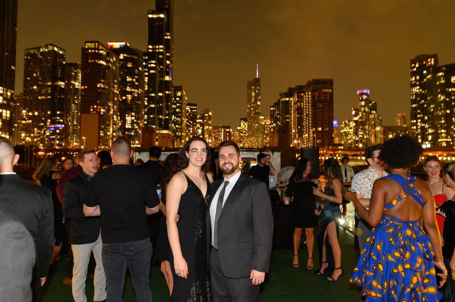 Nighttime rooftop party in Chicago with city lights glowing in background.