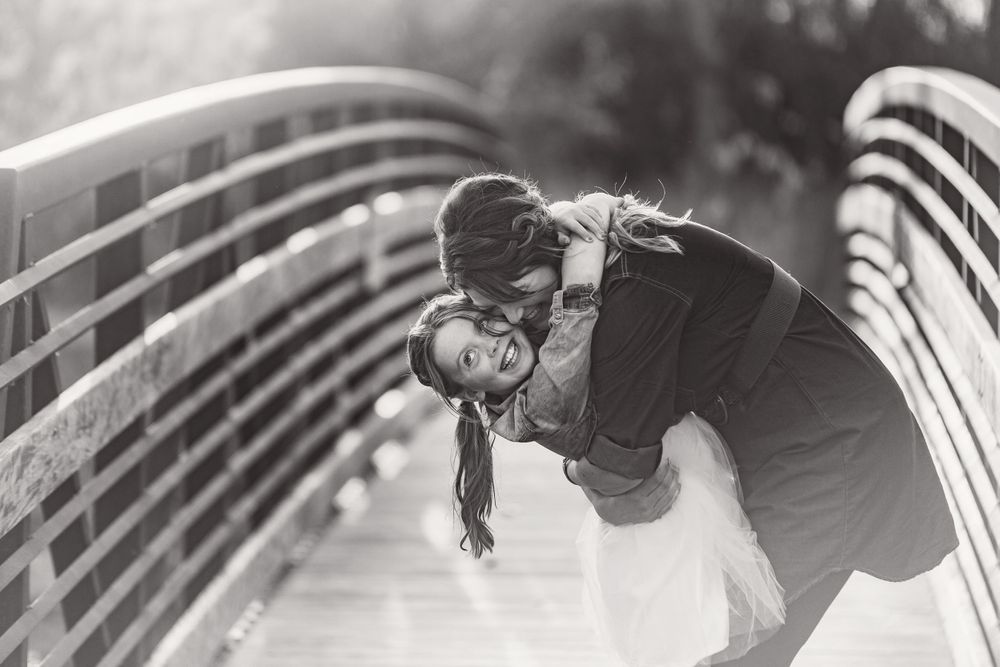 mom and daughter snuggles on bridge, black and white