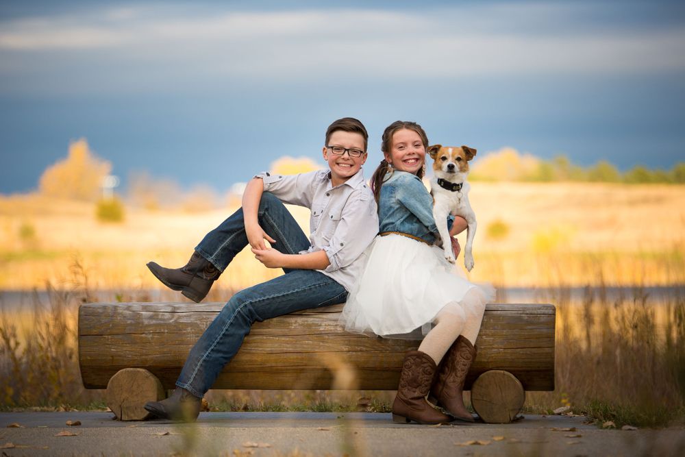 brother and sister with dog on a log bench