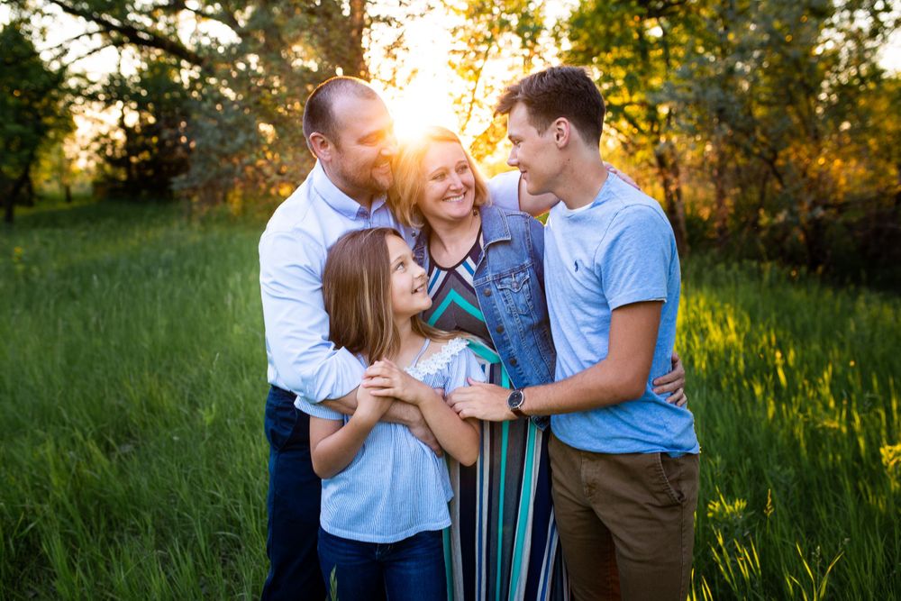 family of four embracing with backlit sun