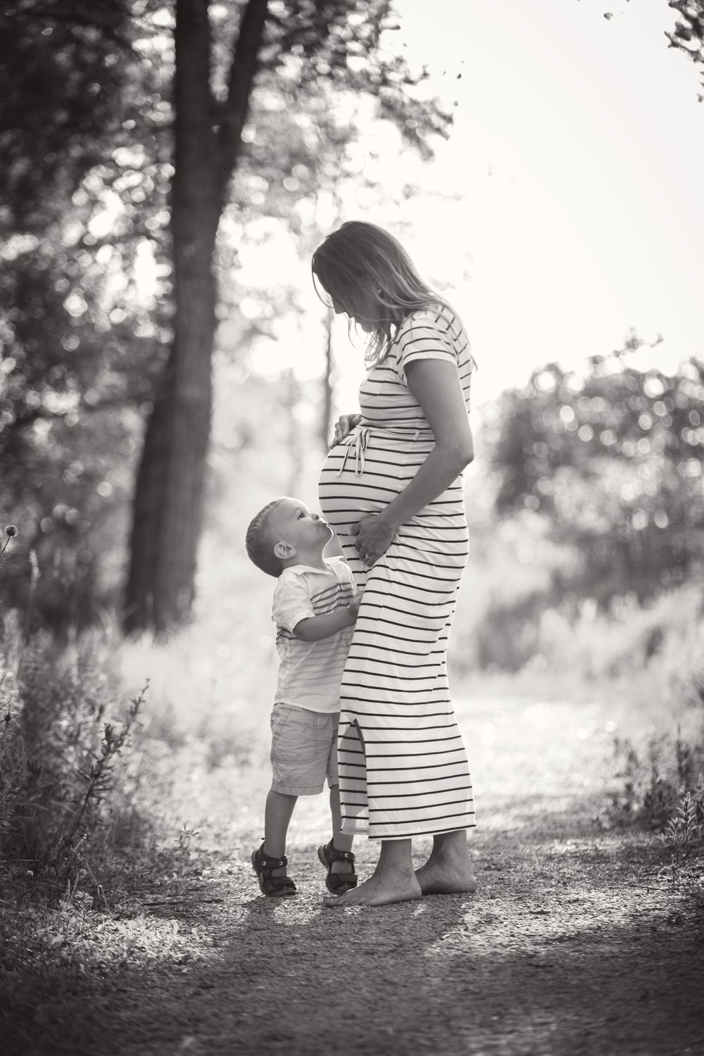 expecting mom and toddler kissing baby bump