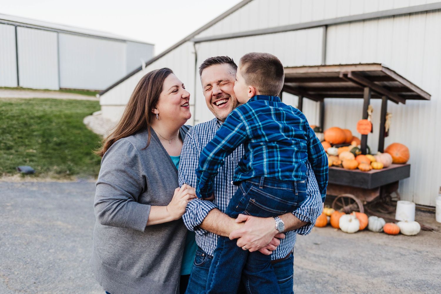 Cute family laughing and candidly joking while getting family photos down at barn in wales wisconsin