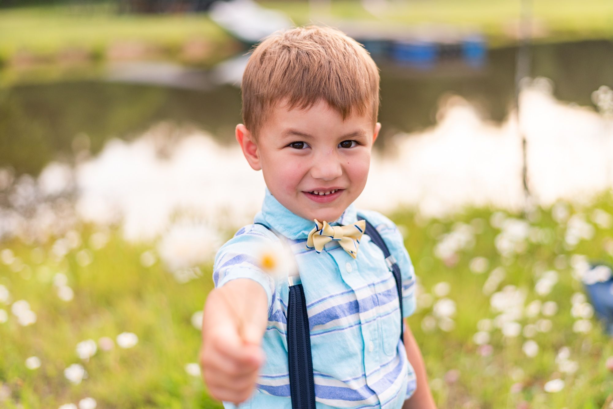 Little boy holding flower in front of pond in Clarion Pennsylvania