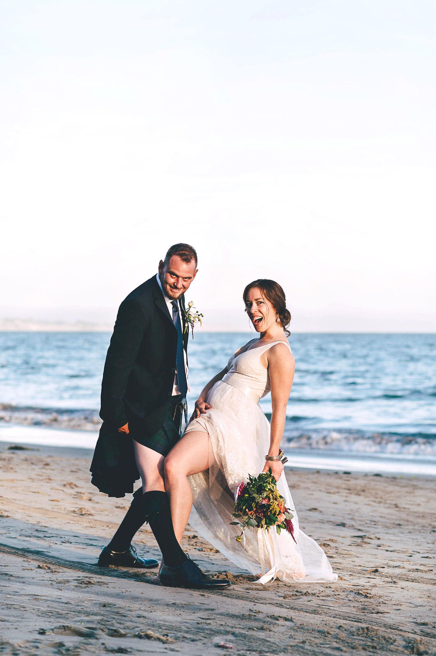 Bride and groom playing on the beach in Santa Cruz at sunset