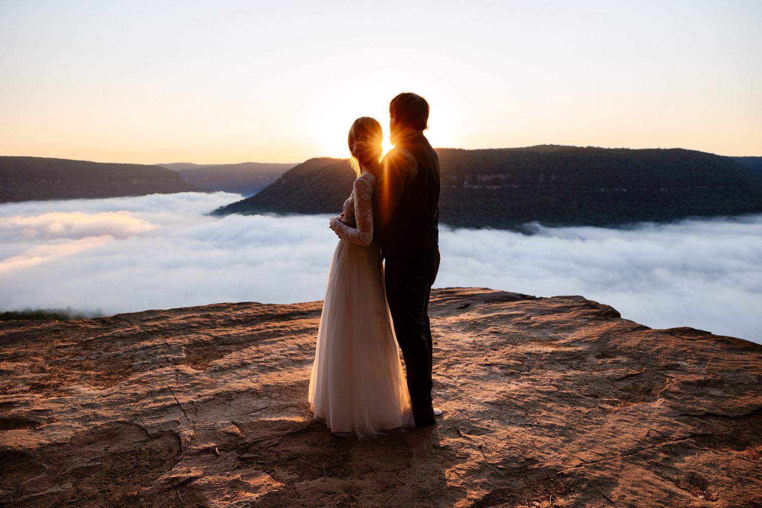 An eloping couple stands facing the sunrise at Snooper's Rock one of the best places to elope in Tennessee.