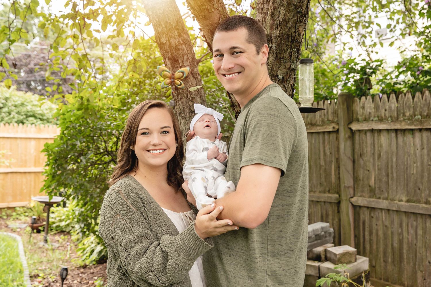 A family poses together in their backyard garden during golden hour sunlight.