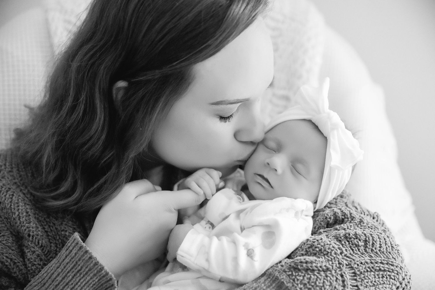 A tender black and white portrait of a mother embracing her newborn baby.