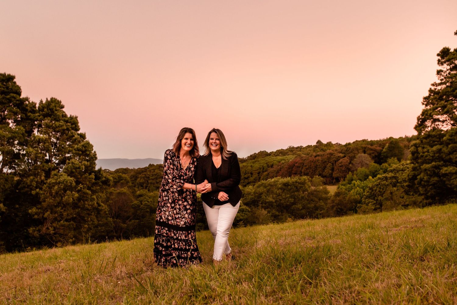 Two women walking through grassland at sunset in Melbourne