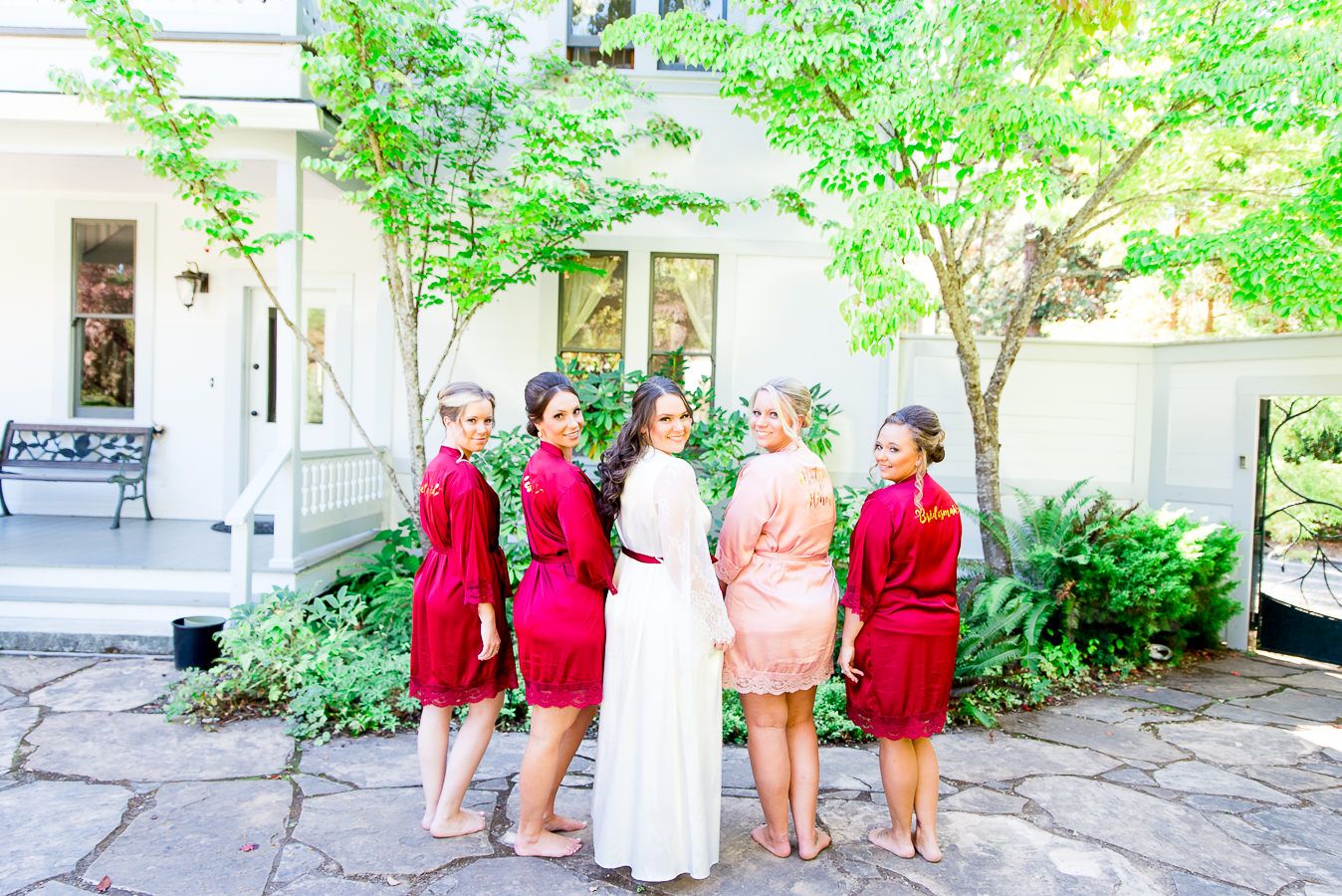 bridesmaids in red and blush stand next to bride on wedding day in September in California
