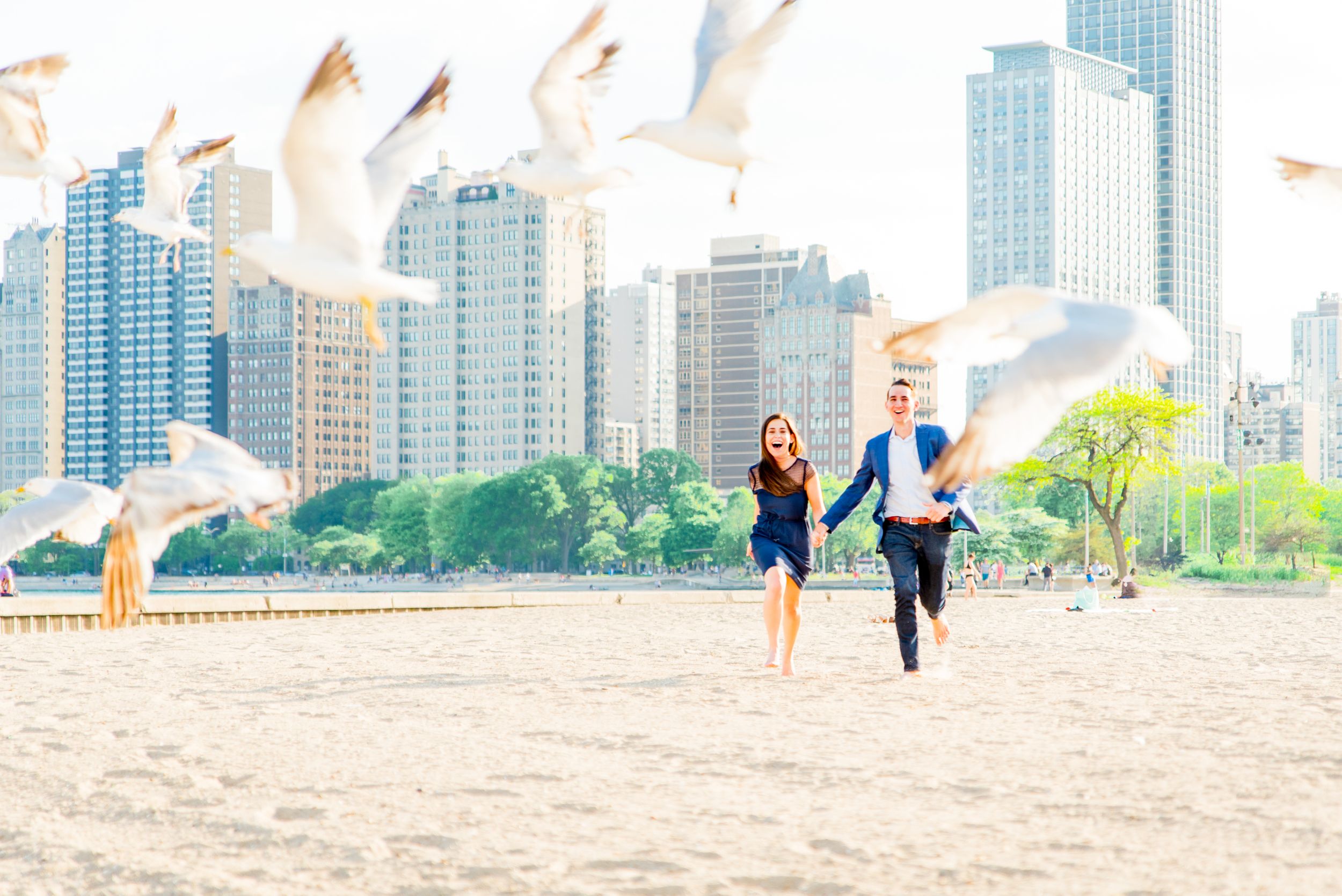 man and woman running through seagulls at North Avenue Beach proposal