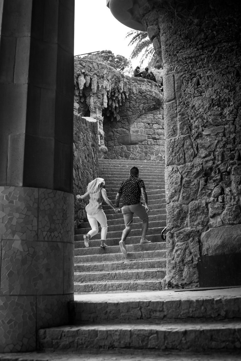 A couple run up the steps of Parc Guell during their engagement photo shoot