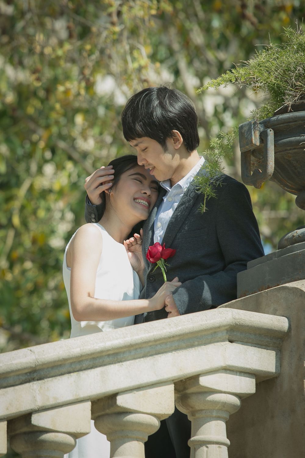 A man embraces his partner on the steps of Parc Cuitadella after their engagement