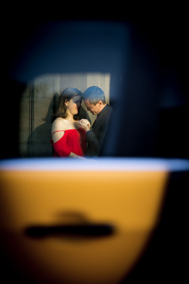 A man proposes which is seen through the window of a passing taxi