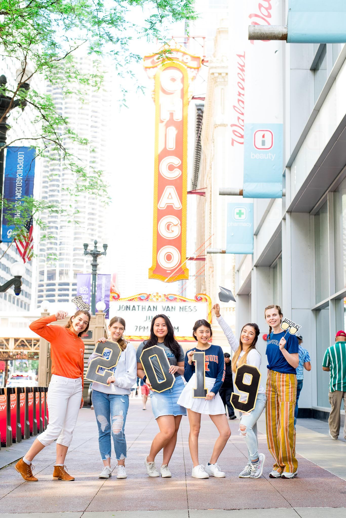 six senior girls in front of the Chicago Theater sign for Chicago senior pictures holding up 2019
