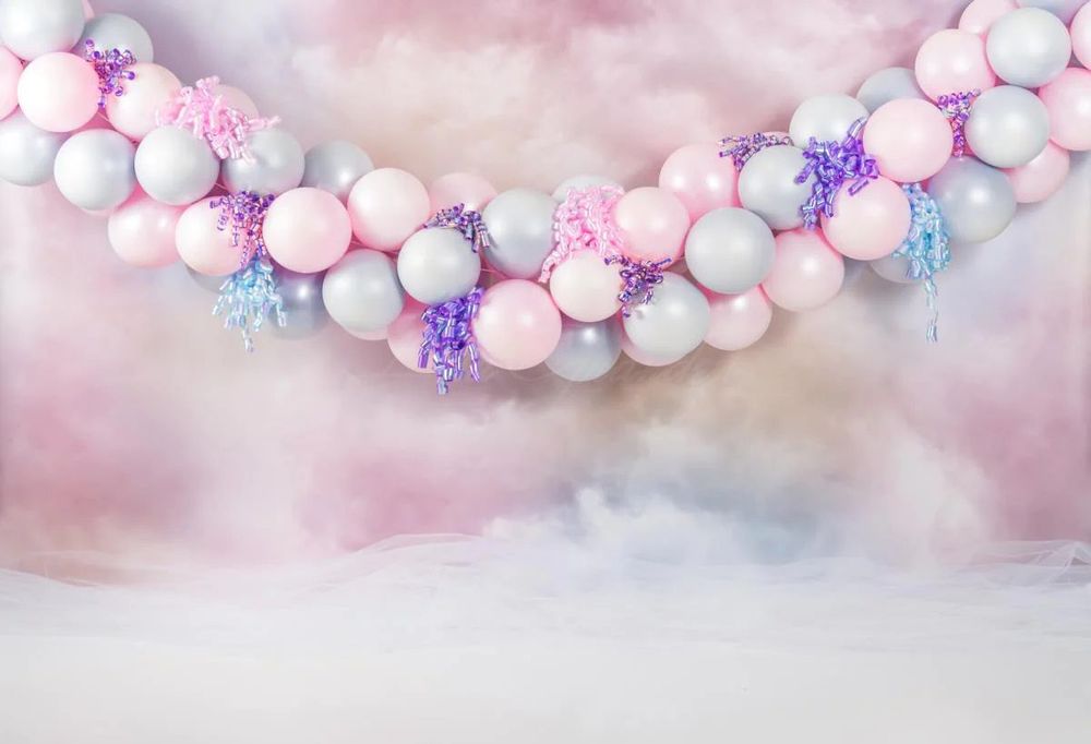 Pastel balloon garland with pink and blue colors against cloudy backdrop.