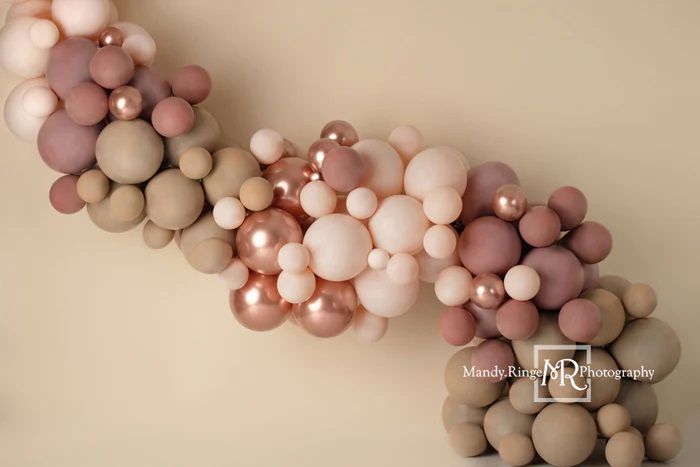 Elegant balloon garland in muted pink and beige tones against neutral background.