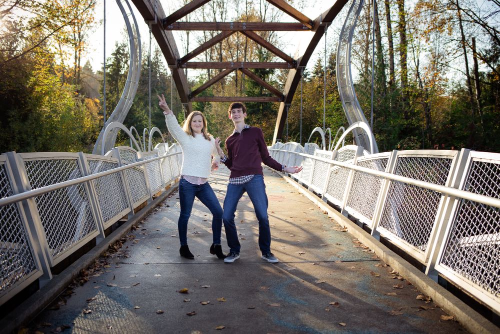 brother and sister being posing silly on a bridge