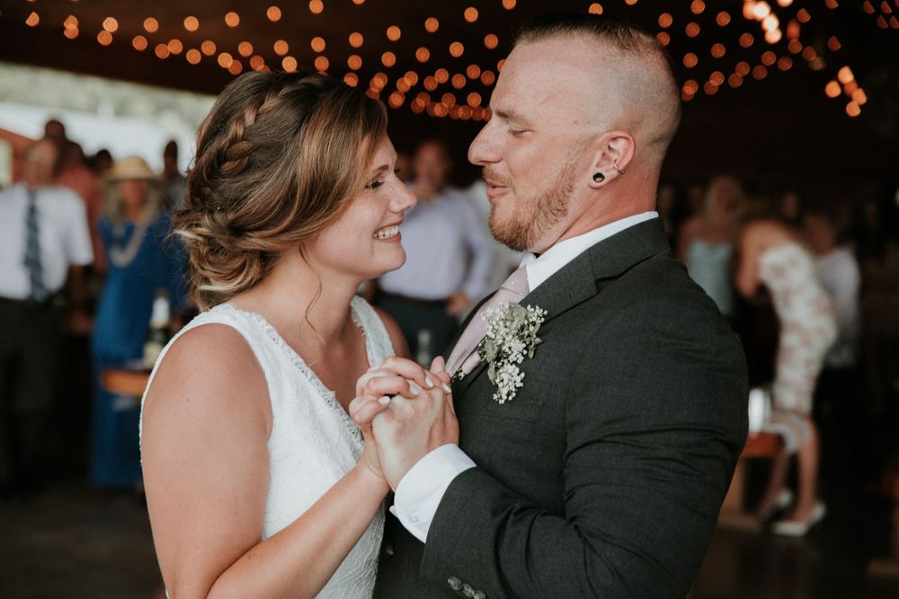 bride smiling at groom who's singing to her during their first dance at climbing bines