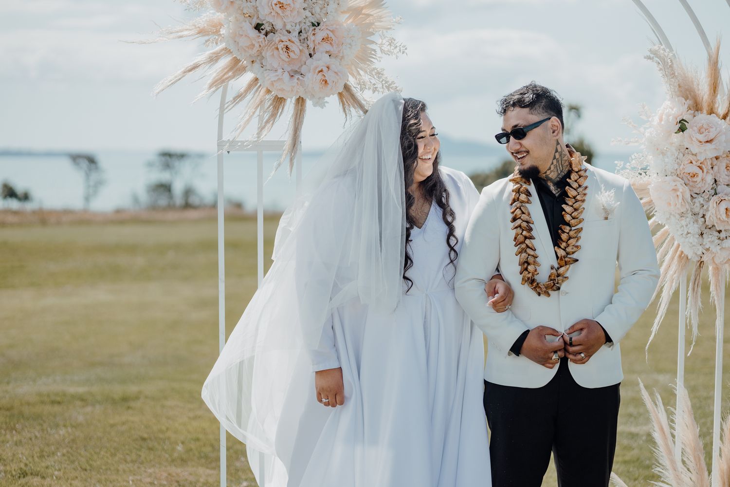 Newlyweds sharing a moment at their beach wedding with pampas grass decorations.