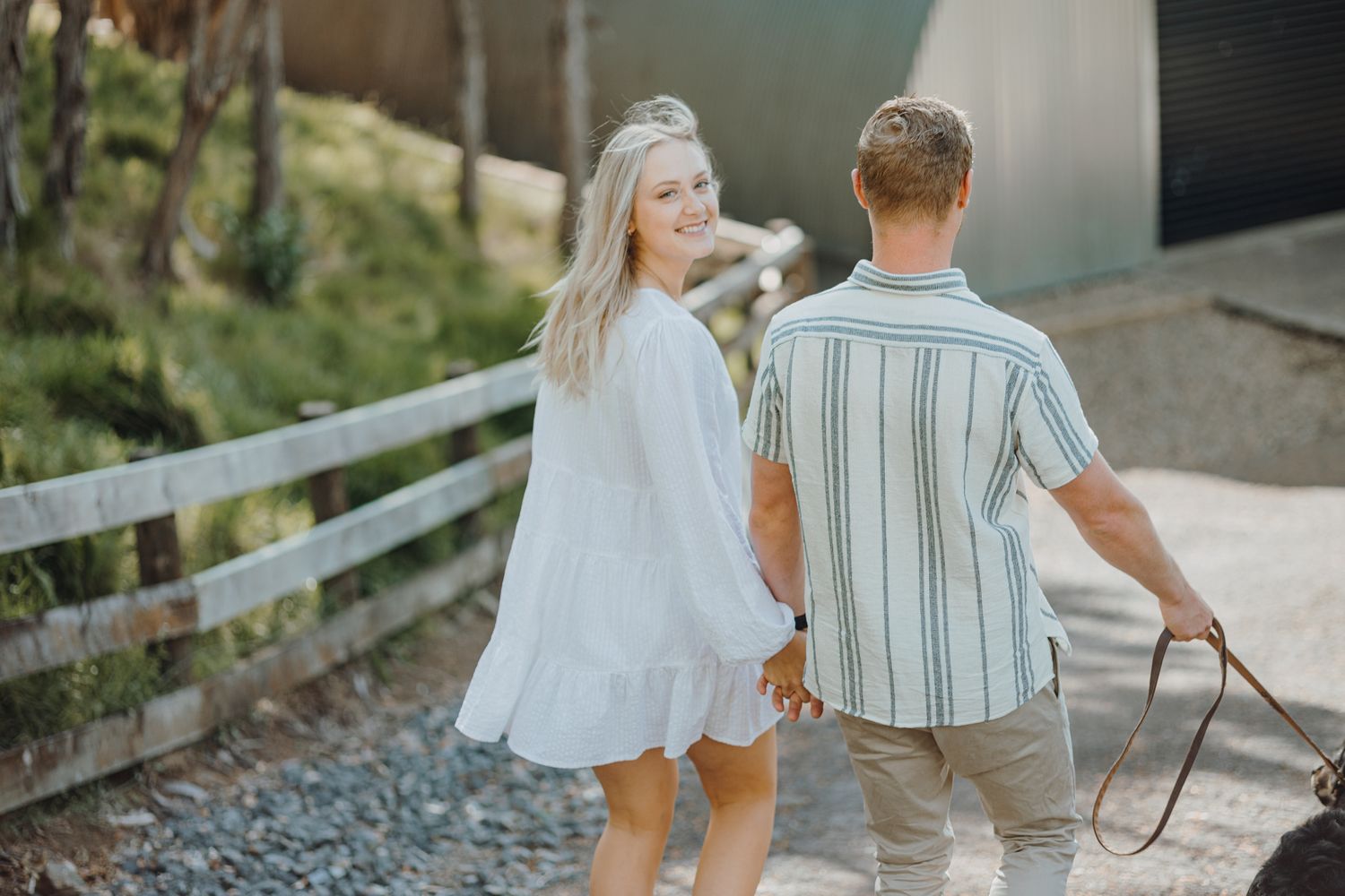 A couple strolls along a wooden walkway surrounded by lush greenery.
