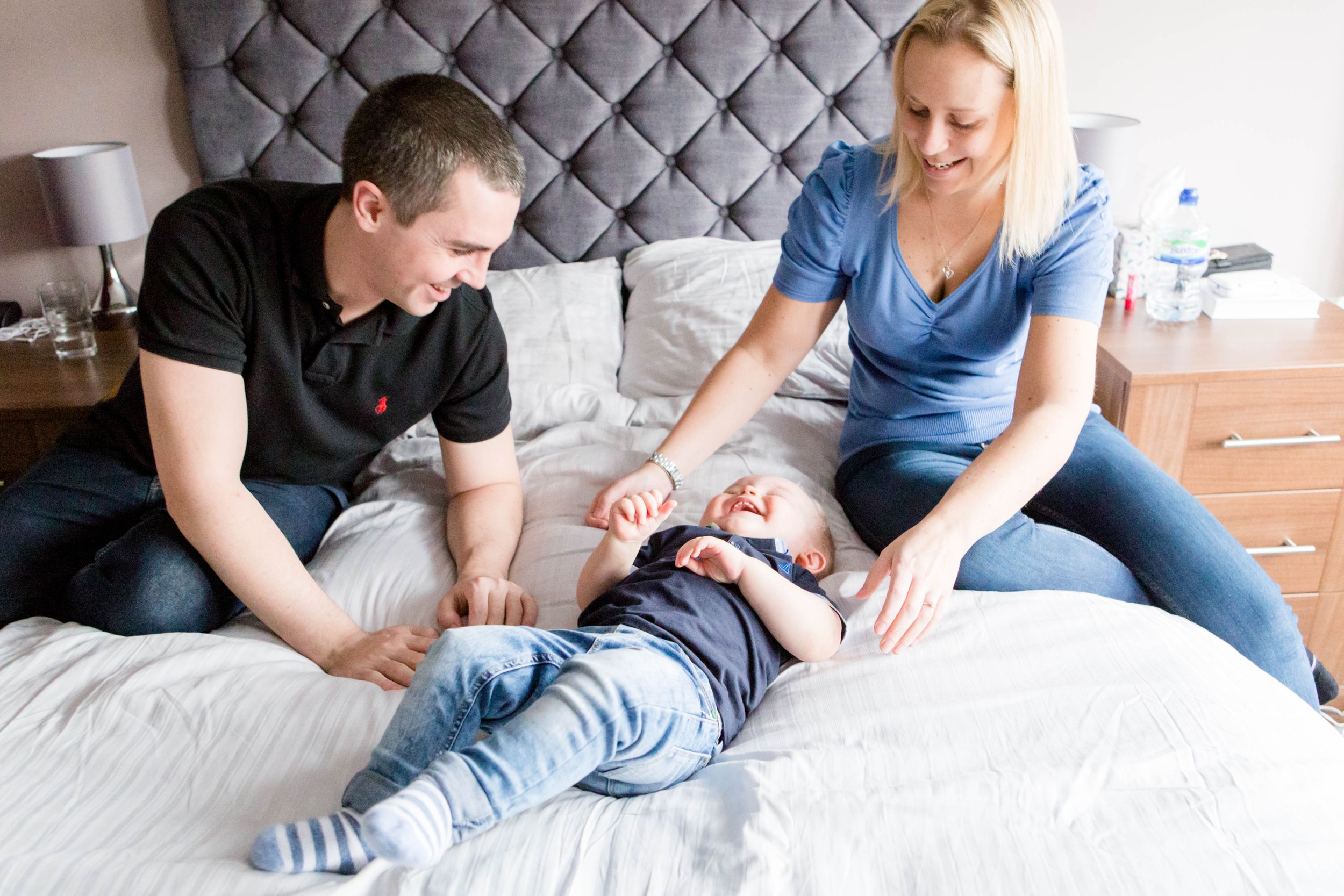 little boy tickled on bed by parents