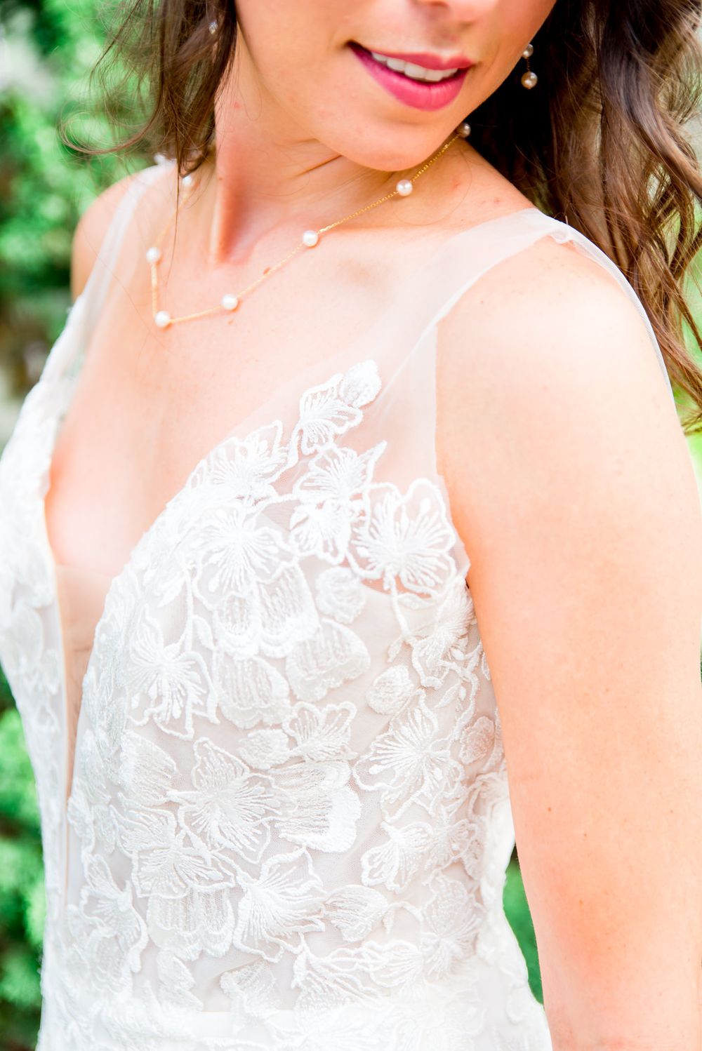 details of Kelly Faetanini Serafina gown and gold and pearl necklace on the dark haired bride