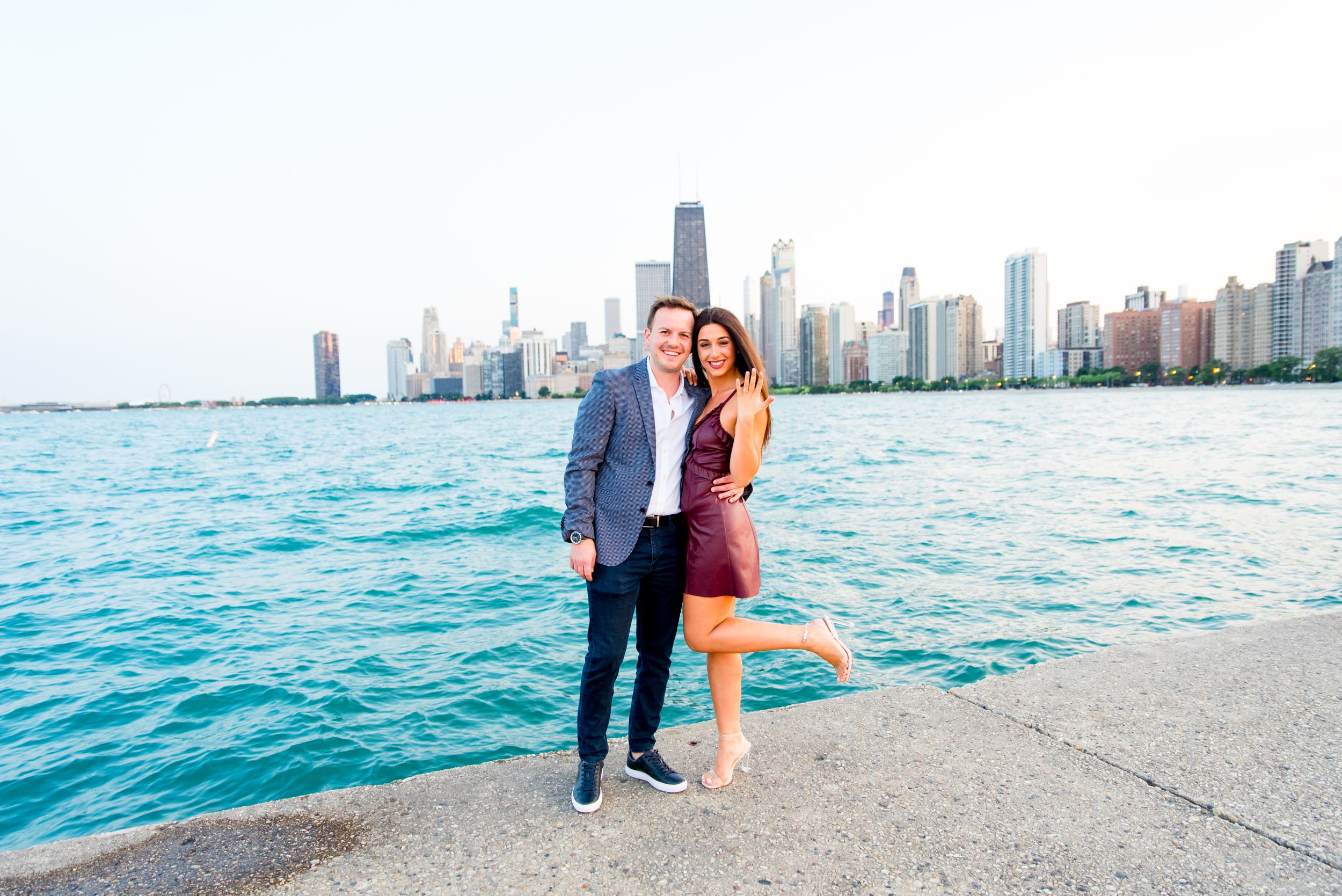 man and woman smiling and woman holding up hand in front of skyline after Chicago Proposal