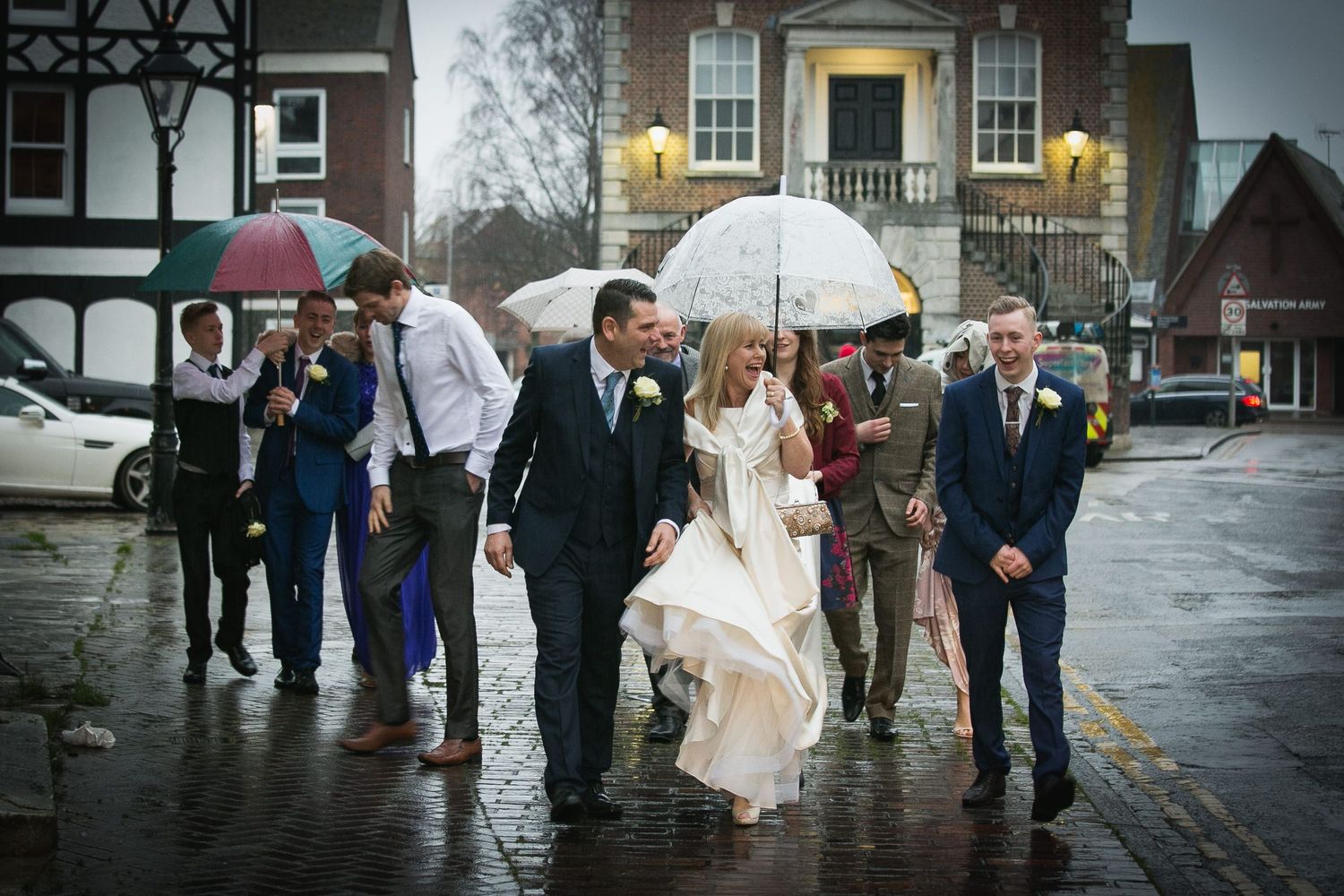 Bride and groom lead their guests through the rain on Poole Quay
