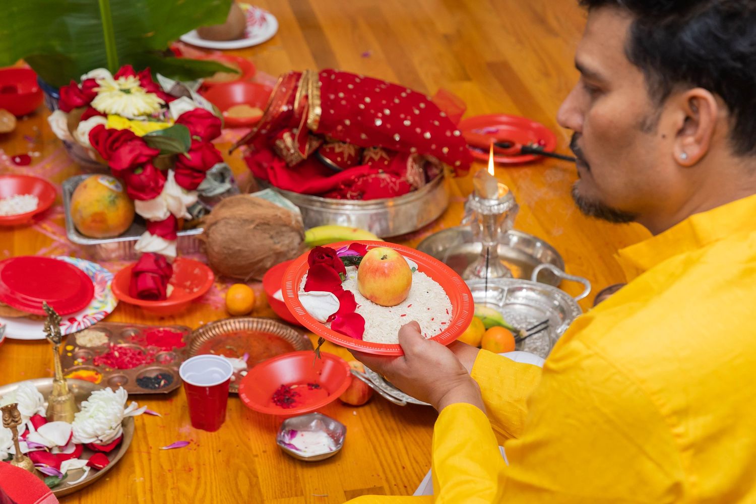 Festive table setting with red decor and traditional items for Hindu ceremony.