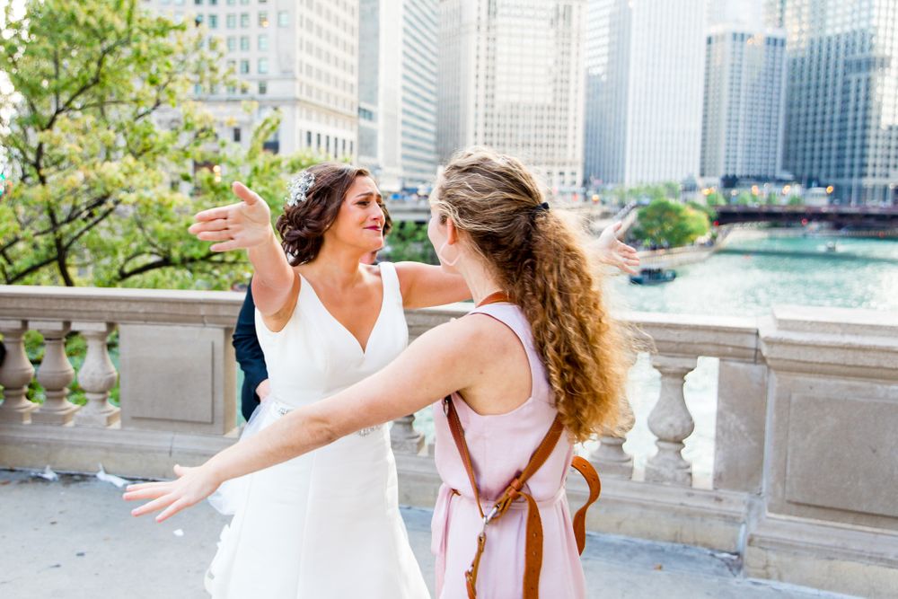 bride and chicago wedding photographer hug near chicago riverwalk and buildings