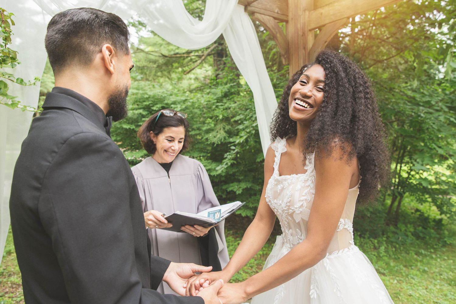 An outdoor wedding ceremony in progress with a couple exchanging vows under natural greenery.