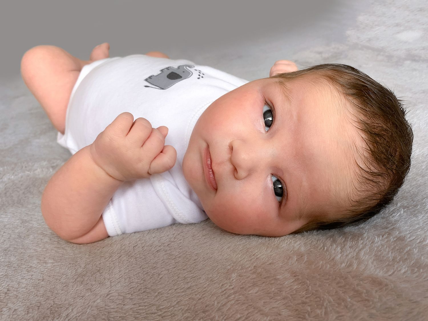 an edited photo of a baby laying on her back looking at the camera from a photo shoot by verity thewlis photography