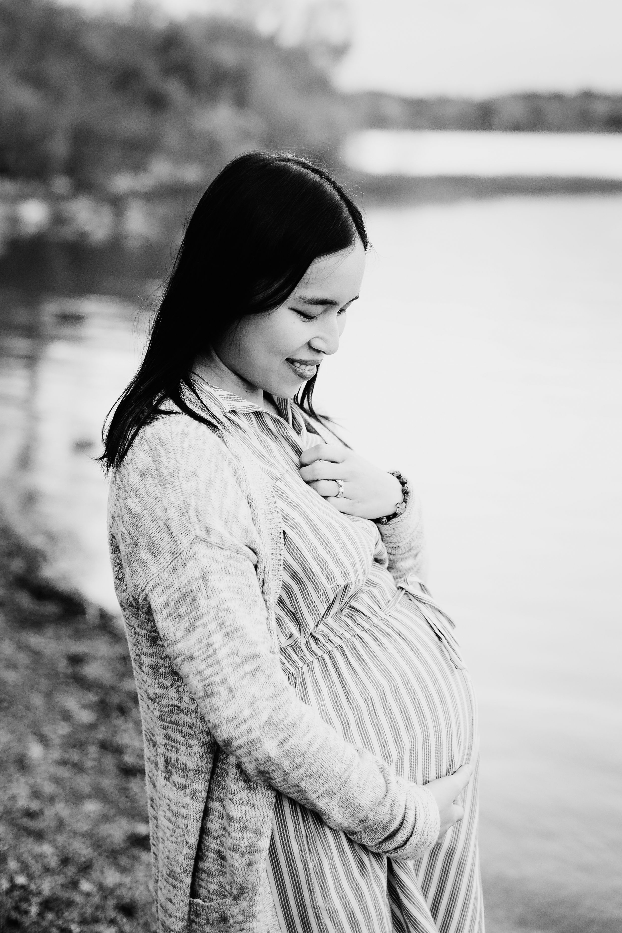 pregnant woman smiling down at belly hand gently on her chest black and white image