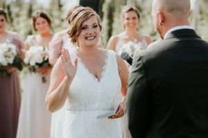 bride giving her vows with her hand raised high back of the groom is in the frame