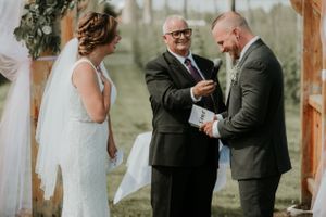 bride, groom, and officiant while groom gives vows