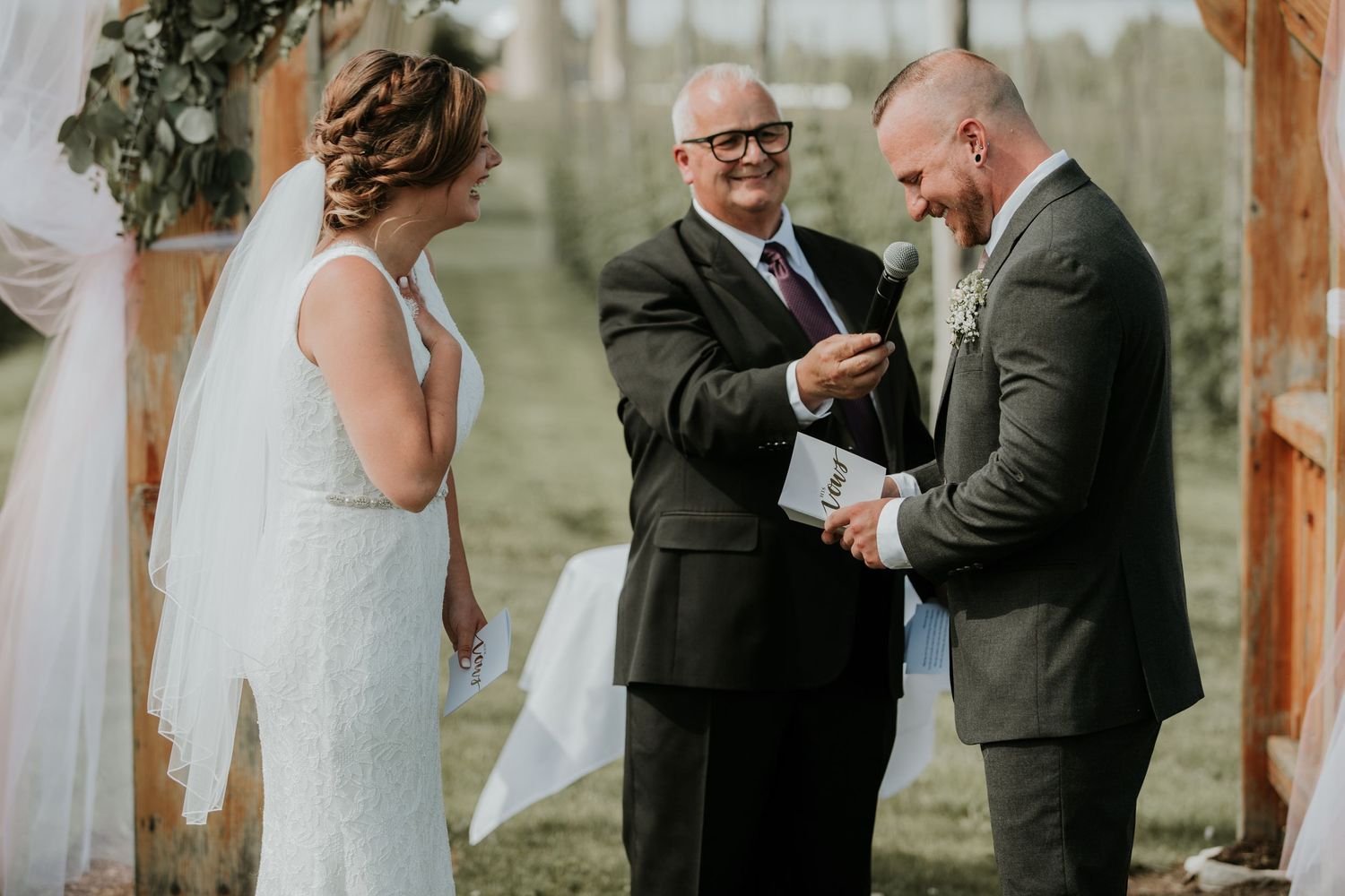 bride, groom, and officiant while groom gives vows