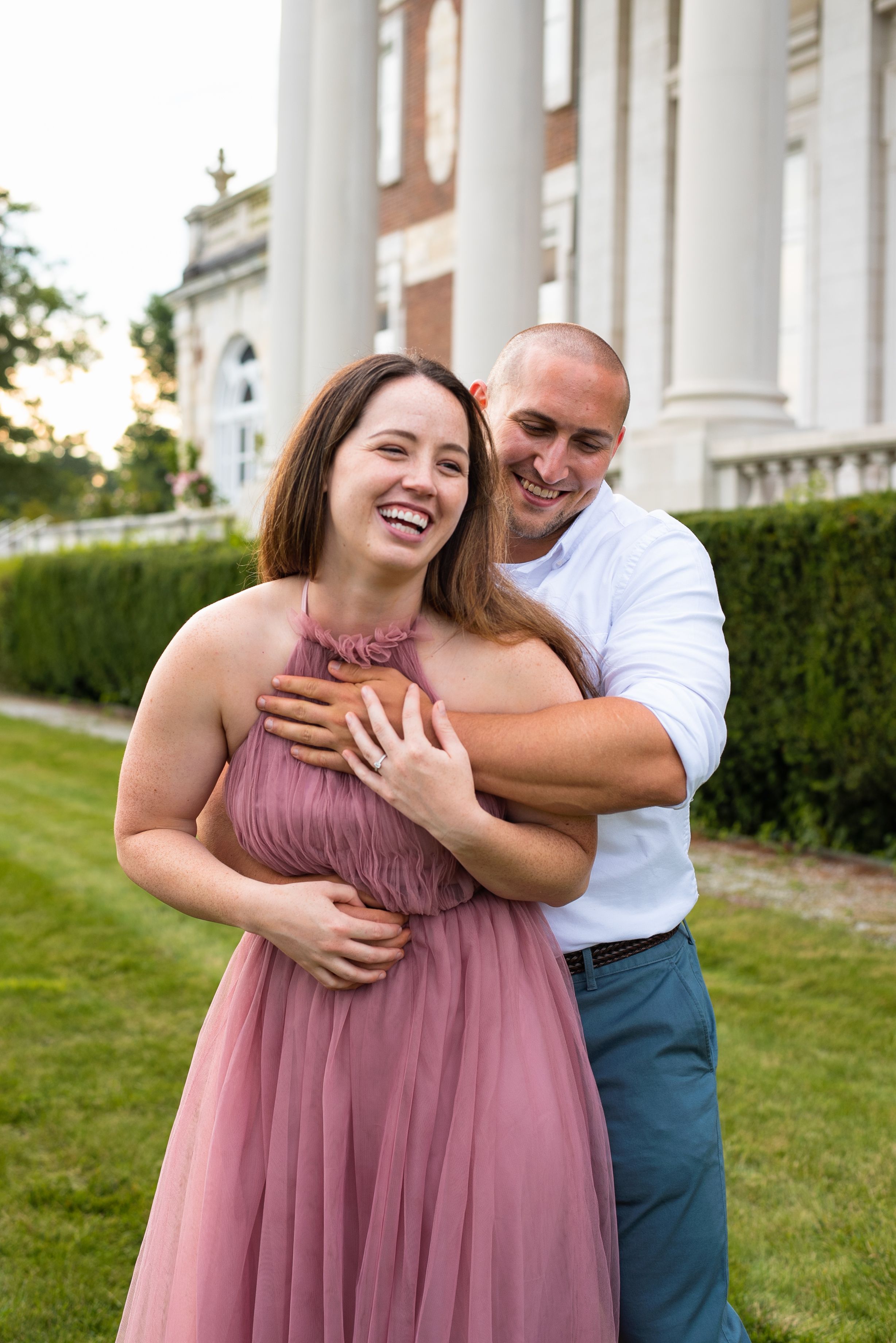 A romantic moment captured outdoors in front of a classical building with white columns.