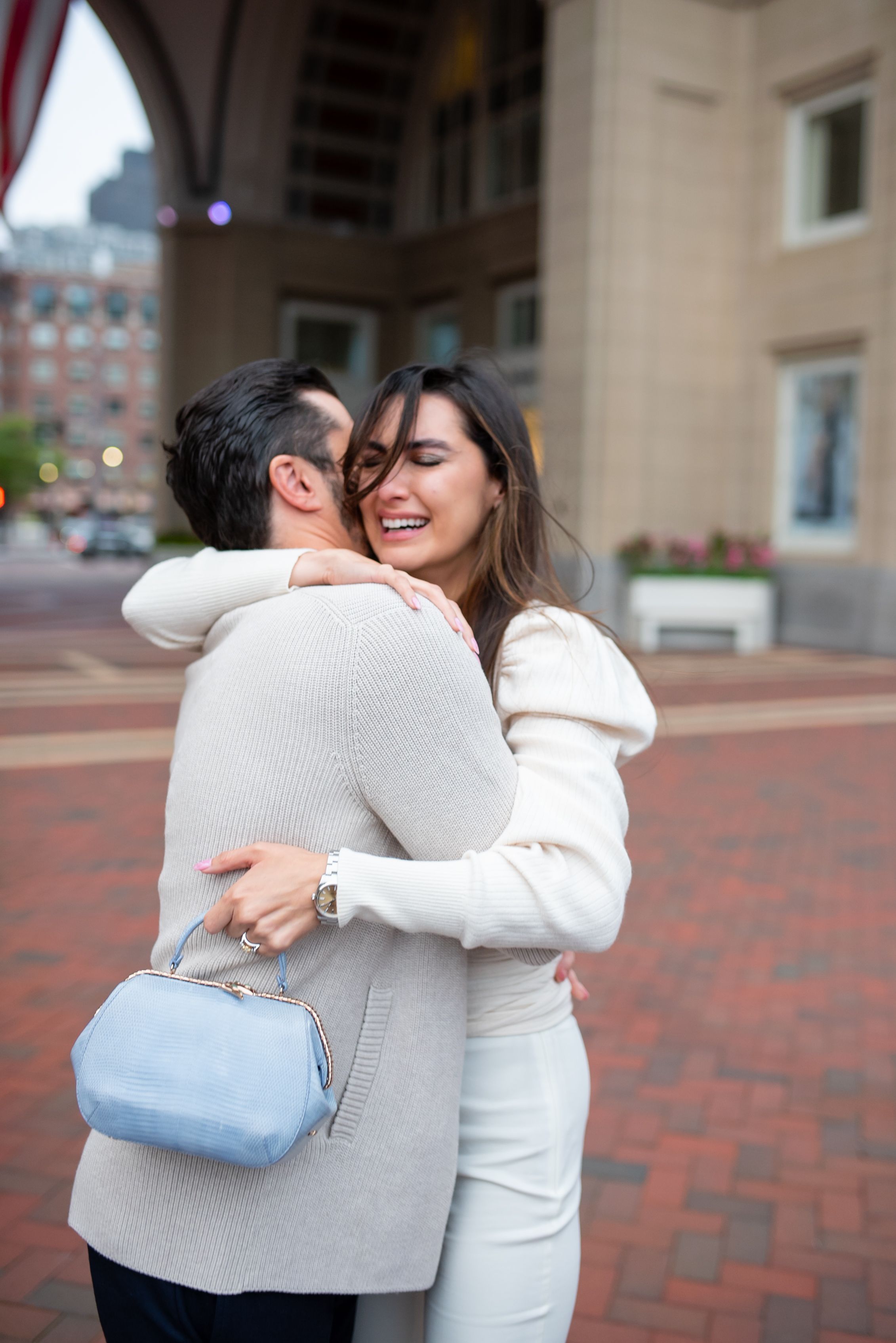 Intimate moment shared between couple embracing on brick-lined urban street.