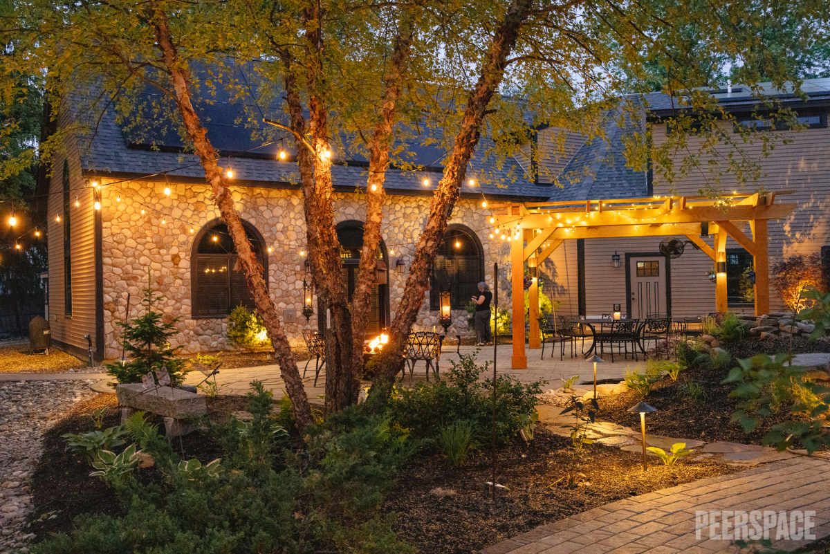 Stone exterior patio with arched doorways and string lights creating a romantic evening atmosphere.
