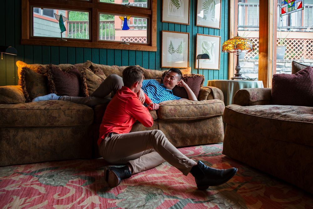 Two gay men relaxing on brown couch in cozy cabin interior of the Guesthouse Lost River.