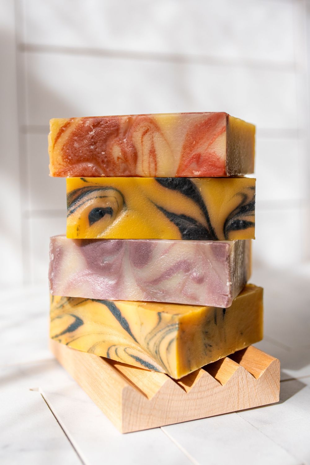 Artisanal handmade soap bars stacked in warm orange and yellow swirled patterns.