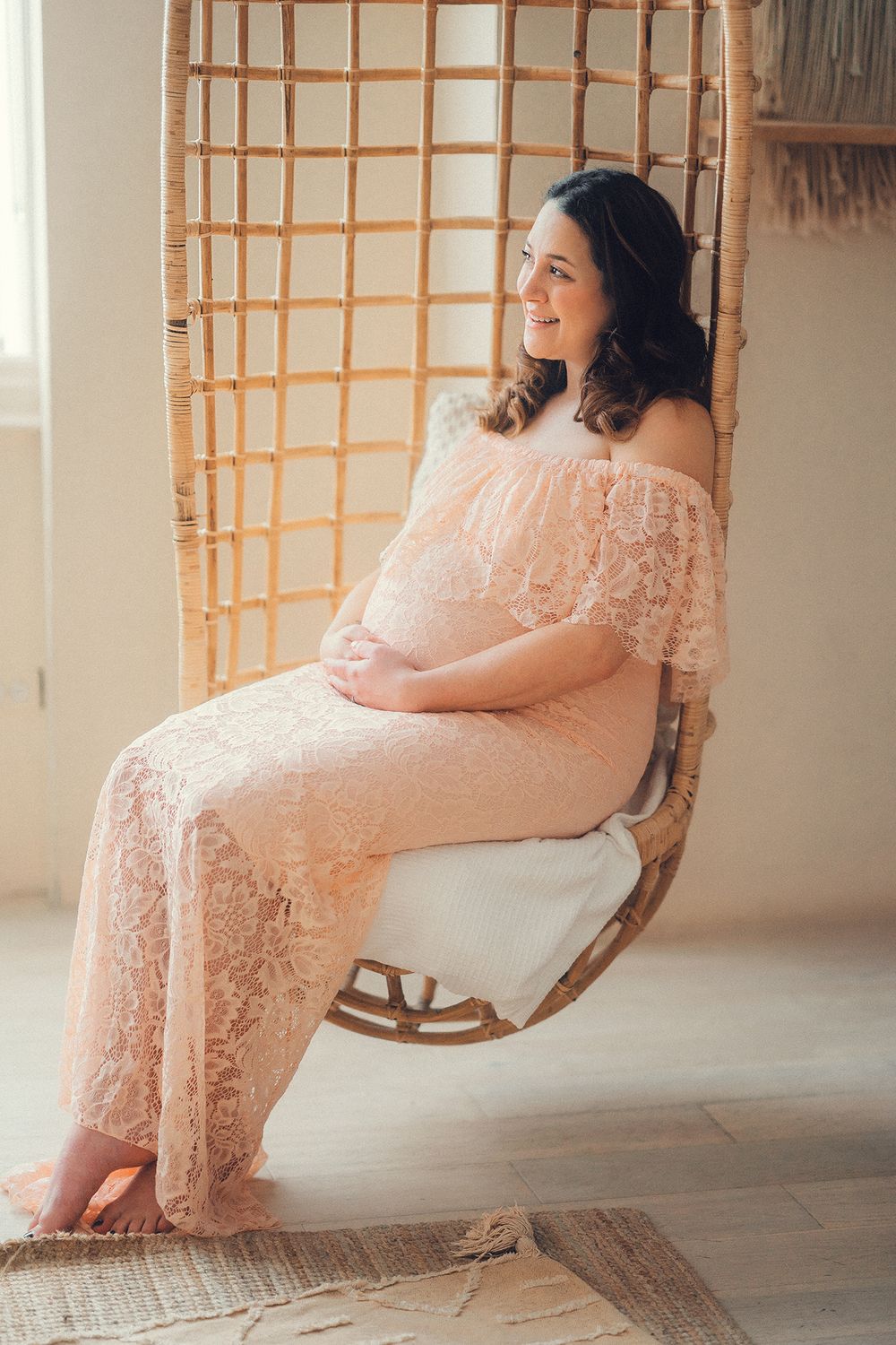 Pregnant woman is sitting in a swing chair at the Mint Room studio in Toronto during the maternity photoshoot
