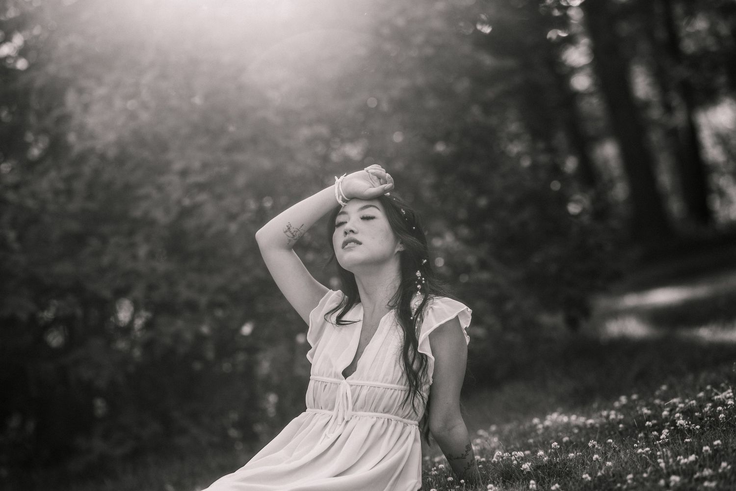 A dramatic black and white portrait in dappled sunlight among trees.