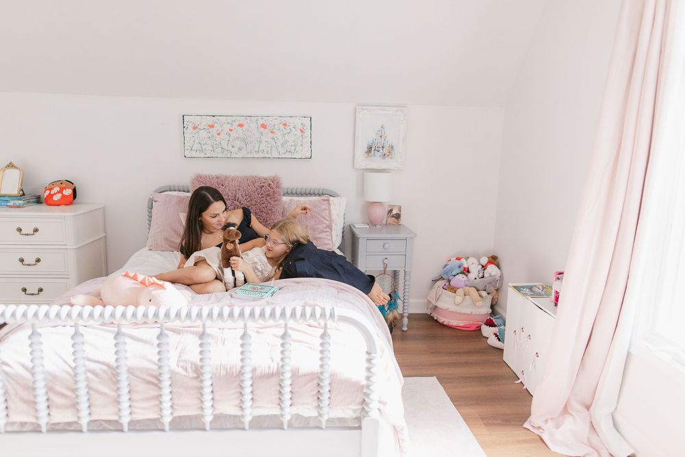 A cozy pink and white bedroom with vintage metal bed frame and plush stuffed animals decorating the space.