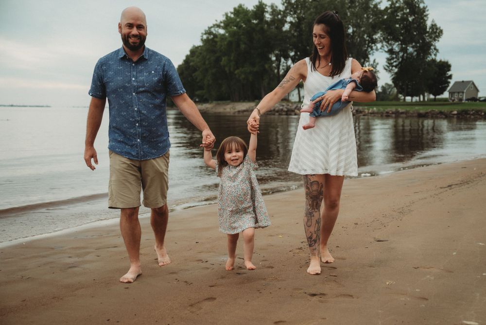 Family walking together barefoot along peaceful beach shoreline.