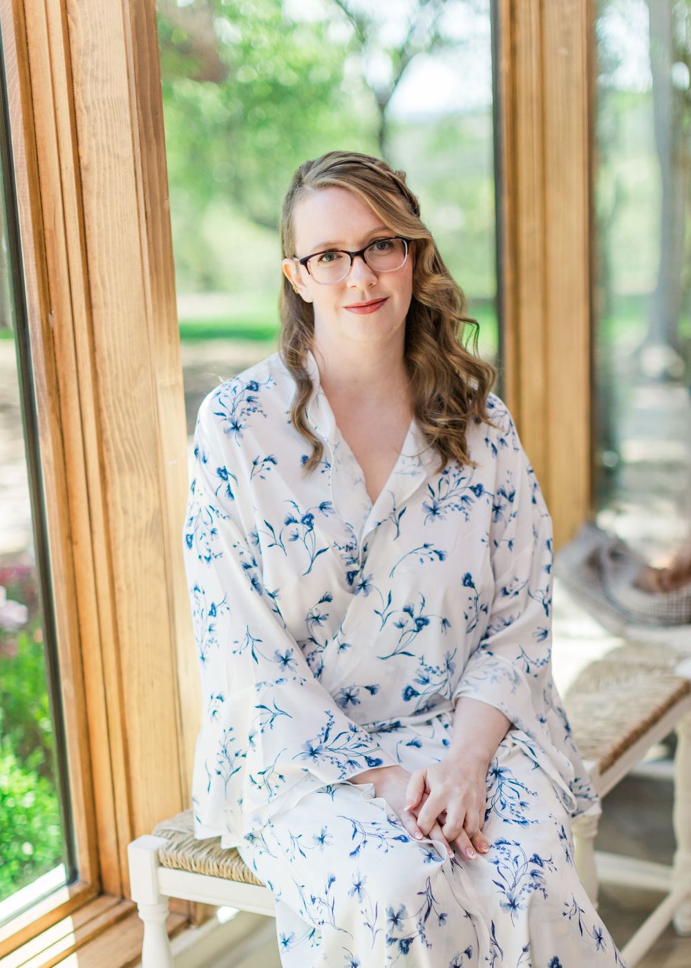 Person in white and blue floral robe sitting by window in morning light.